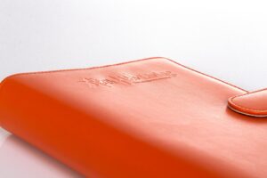 Orange leather-bound notebook on white background.