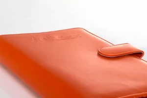 Orange leather notebook with strap closure.