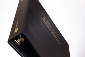 Black binder with gold lettering, angled view.