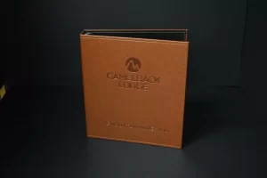 Brown Camelback Lodge binder on dark background.