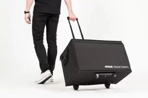 Person pulling black wheeled suitcase, white background.