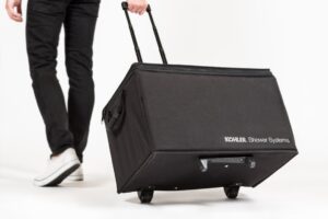 Person pulling large black wheeled suitcase.