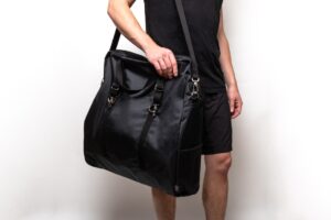 Person holding a large black shoulder bag.