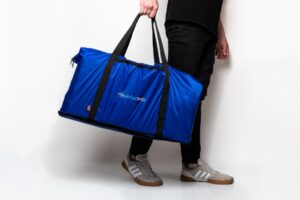 Person holding large blue duffel bag.