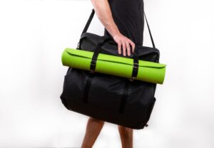 Person carrying bag with green yoga mat.